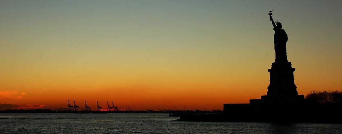 The statue of Liberty in front of a sunset.