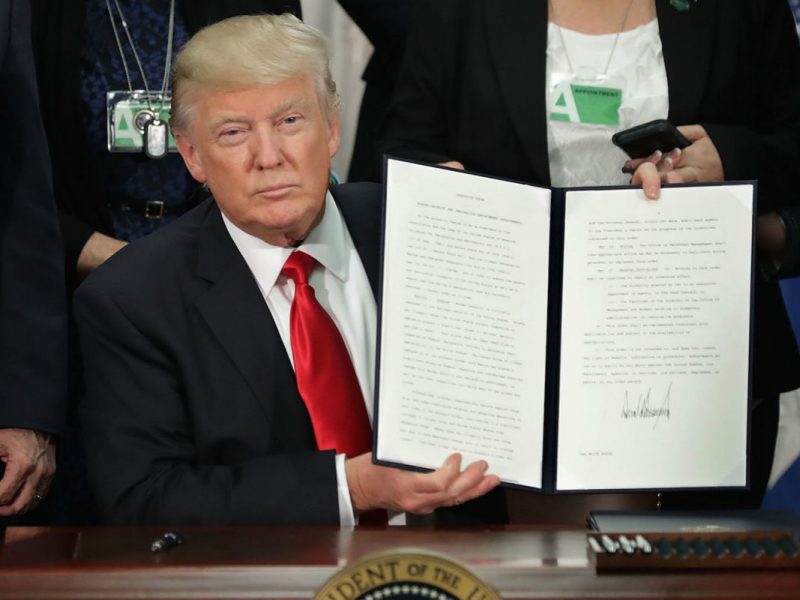 Picture of Donald Trump in Oval Office Holding up immigration Executive Orders